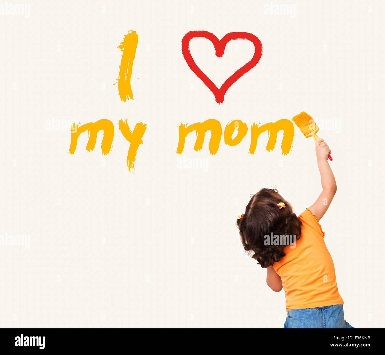 Petite fille écrit 'J'aime ma maman" avec le pinceau sur le mur Banque D'Images