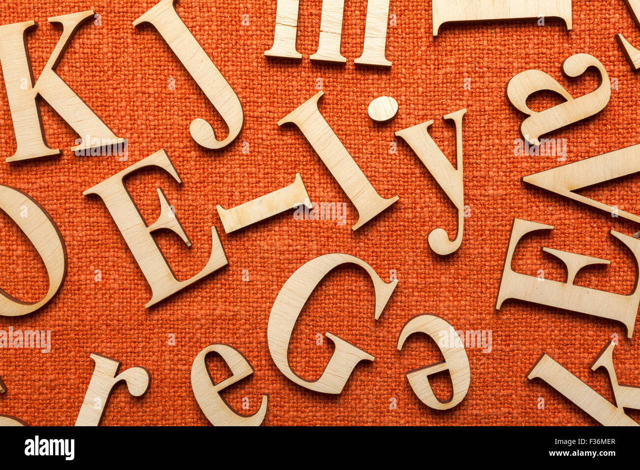 Lettres alphabet en bois sur la surface du tissu orange avec de l'espace pour votre propre texte. Banque D'Images