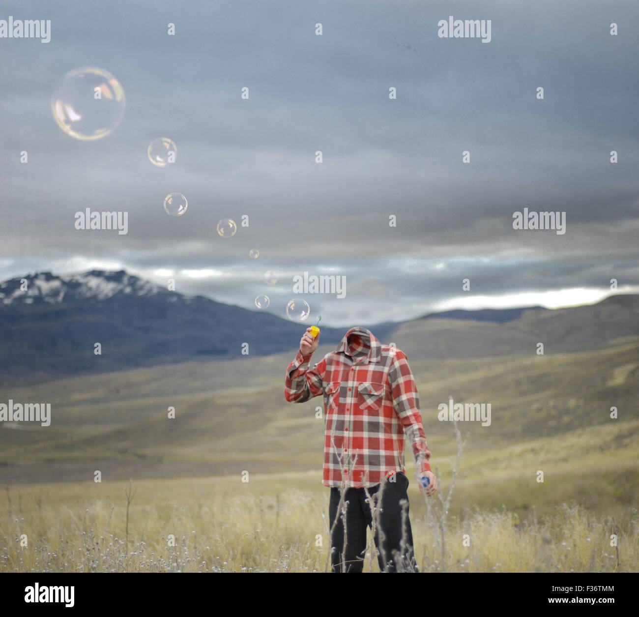 L'homme sans tête blowing bubbles montagne ciel orageux Banque D'Images