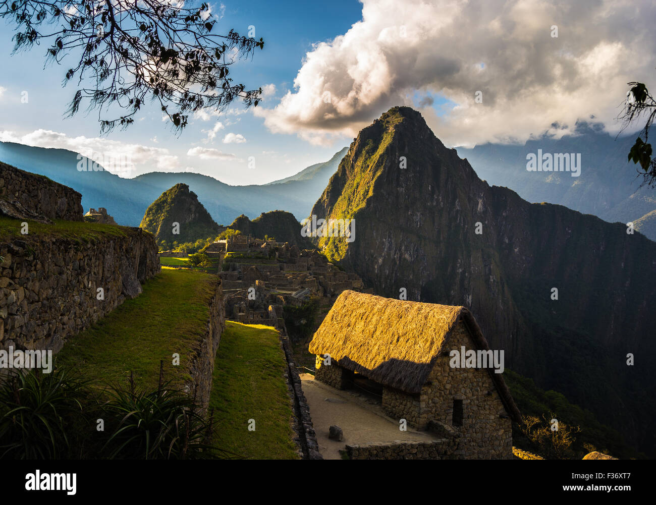 Machu Picchu partiellement éclairée par la dernière lumière du soleil. Vue grand angle de la terrasse avec vue panoramique et ciel de toit lumineux en t Banque D'Images