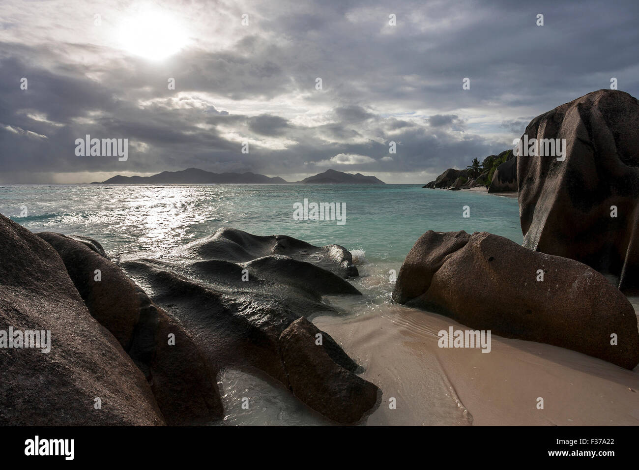 Plage et rochers de granit à l'Anse Source d'argent avec des nuages sombres, île de Praslin, derrière l'île de La Digue, Seychelles Banque D'Images