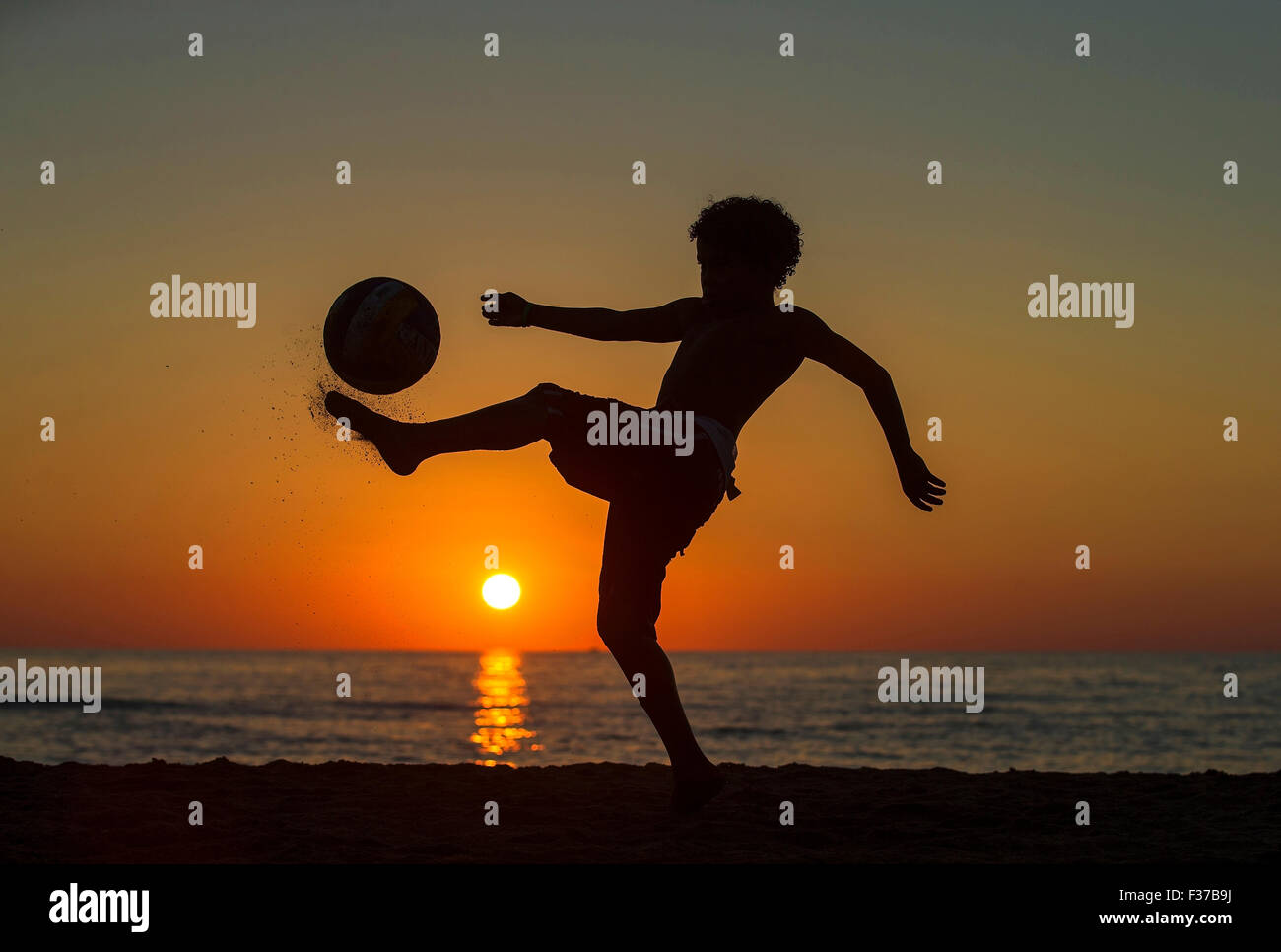 Garçon avec ballon de soccer, coucher du soleil à la mer, plage, Italie Banque D'Images