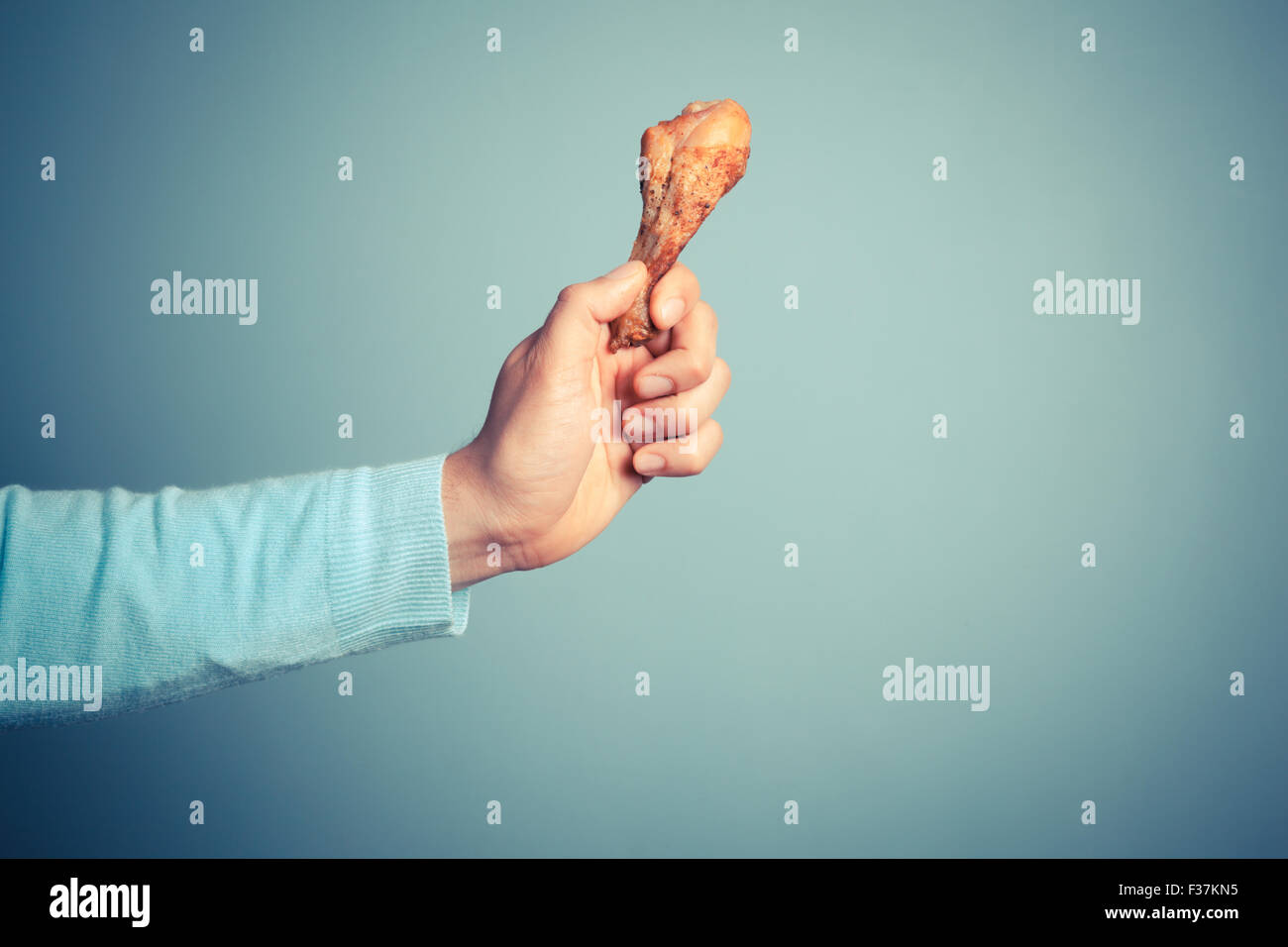 Un jeune homme se tenant une pilons de poulet rôti Banque D'Images