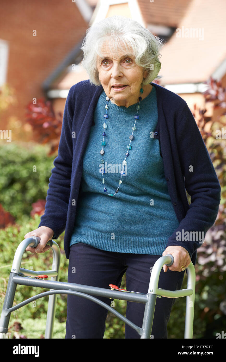 Senior Female dans Garden en utilisant Déambulateur Banque D'Images