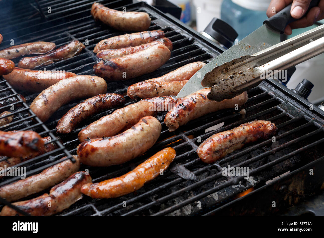 Man cooking sausages sur la grille du barbecue - USA Banque D'Images