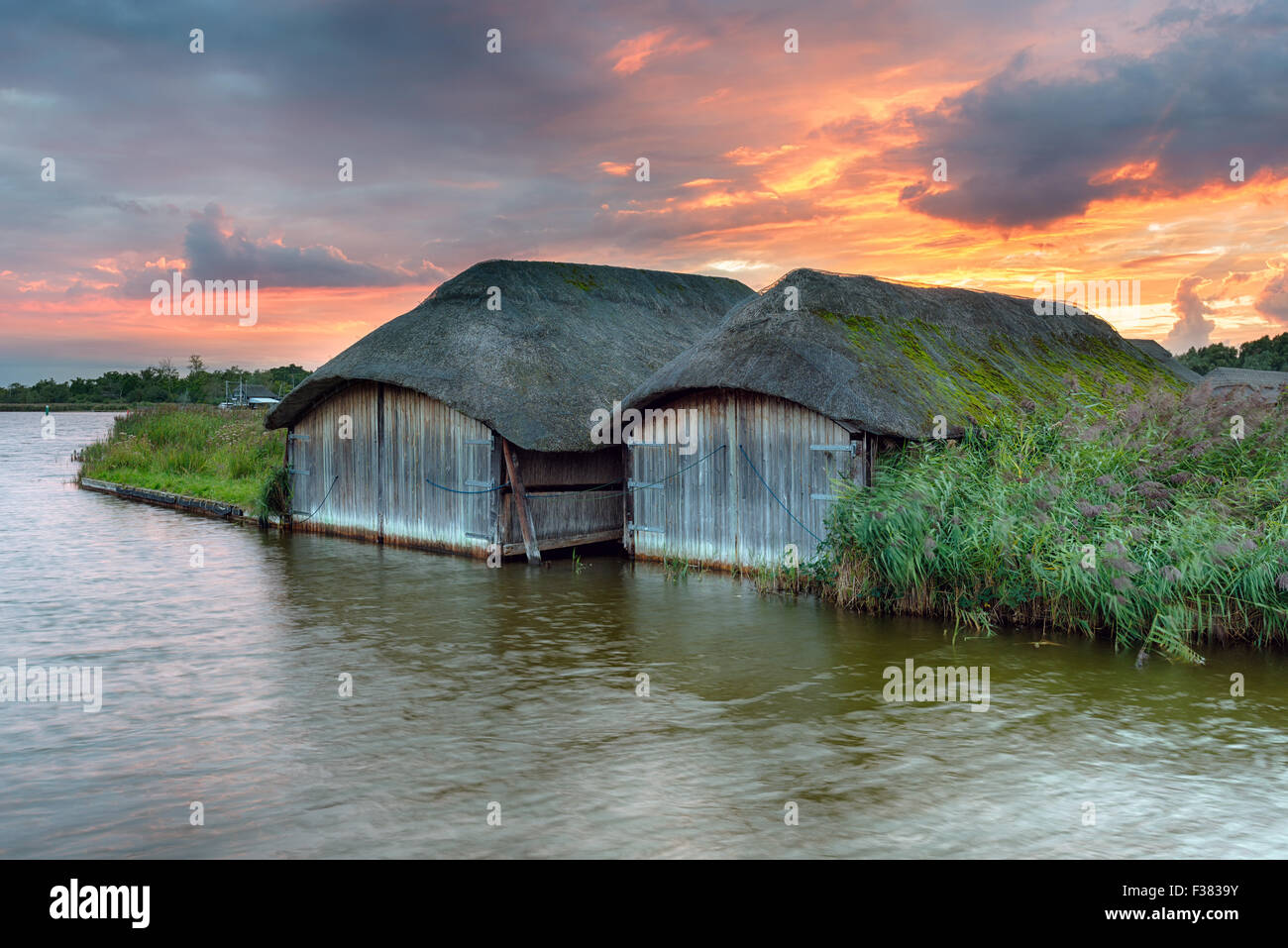 Magnifique coucher de soleil sur Fiery bateau chaume maisons sur les Norfolk Broads à Hickling Banque D'Images