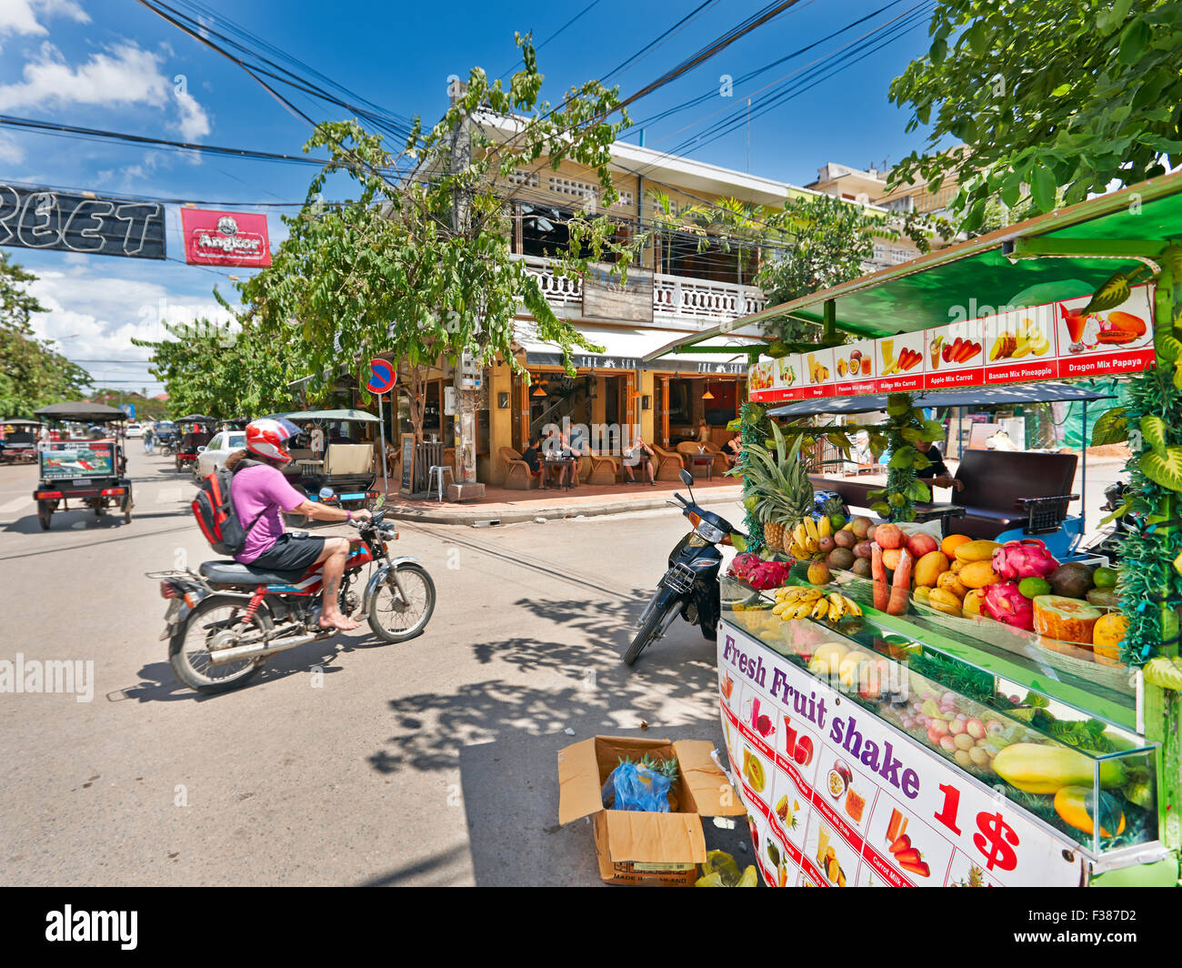 L'homme en vélo passant par un étal de fruits dans l'ancien quartier français de Siem Reap, au Cambodge. Banque D'Images