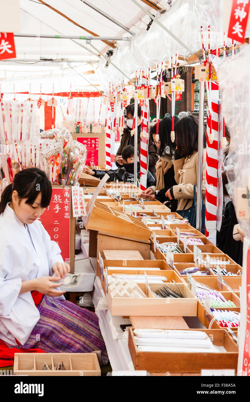 Kyoto, temple shintoïste Yasaka lors du festival du Nouvel an. Les personnes qui achètent, engimono bonne chance charms, de la ligne de stands de culte maidens, Miko. Banque D'Images