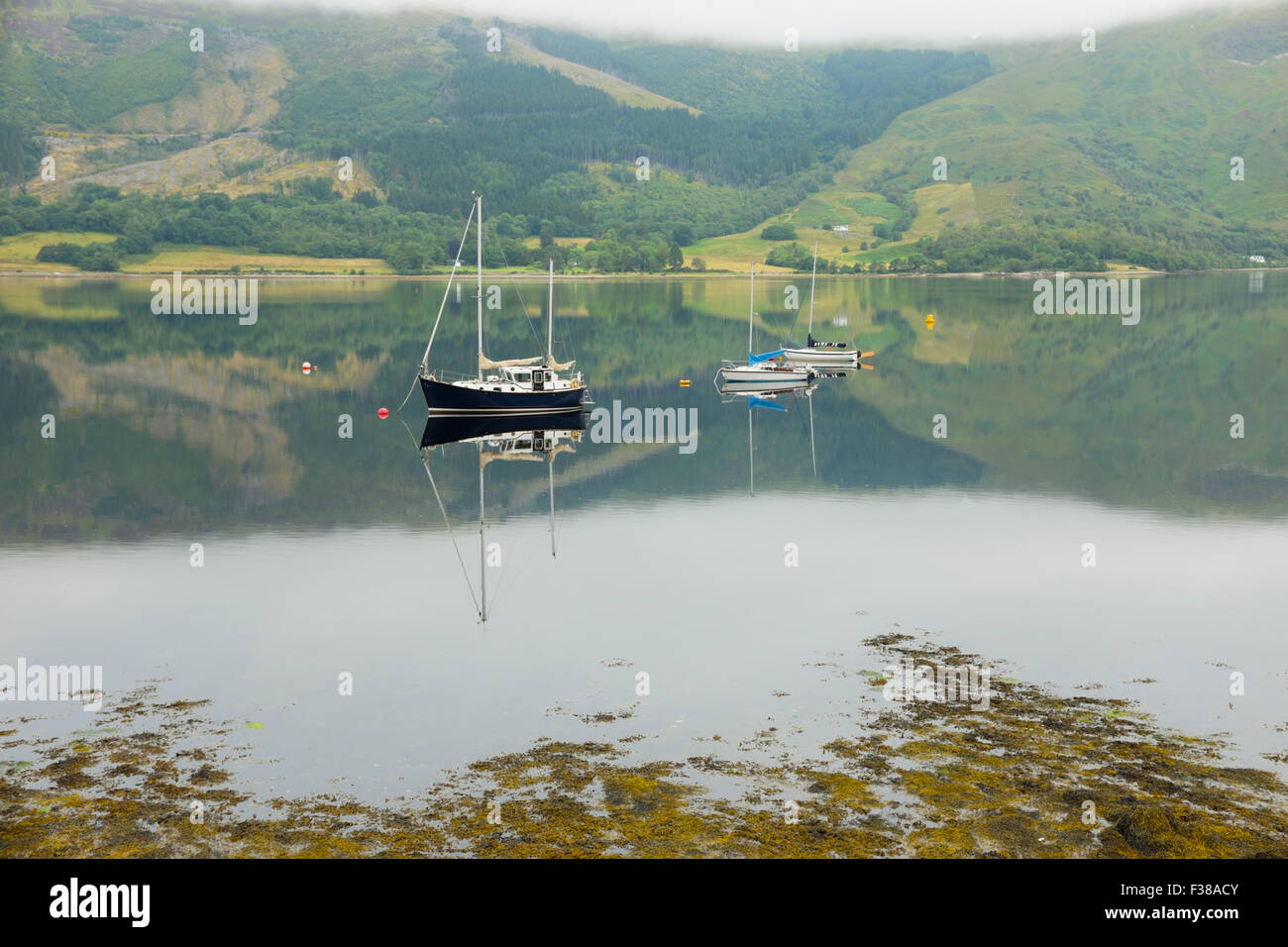 Bateaux amarrés sur une calme Loch Leven. Banque D'Images