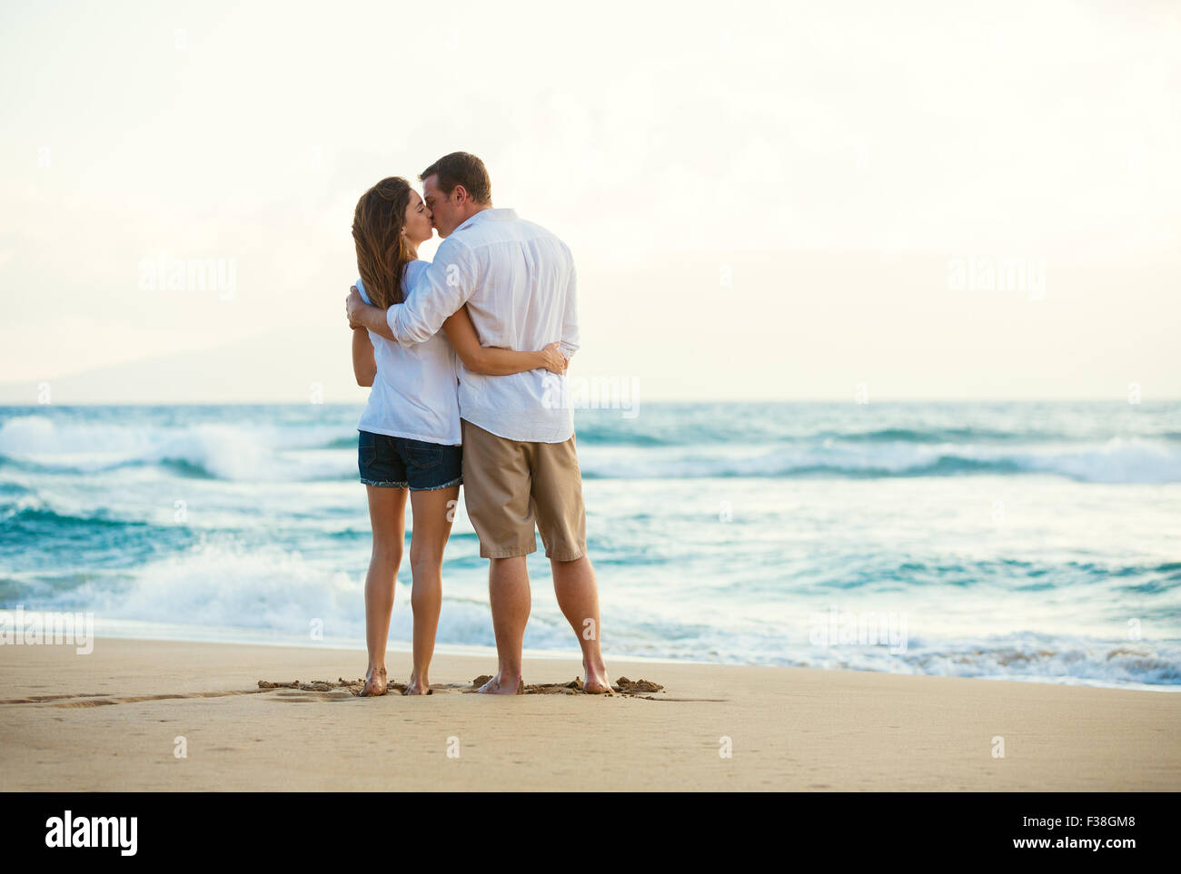Heureux Couple romantique sur la plage au coucher du soleil Banque D'Images