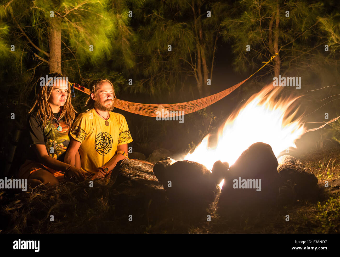Feu de camp sur une plage rocheuse avec couple sitting Banque D'Images
