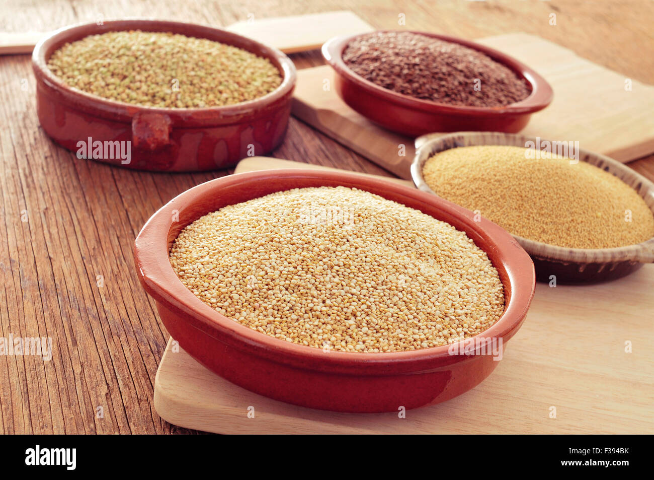 Certains bols en terre cuite avec l'amarante, le quinoa, lin brun et le sarrasin graines sur une table en bois rustique Banque D'Images