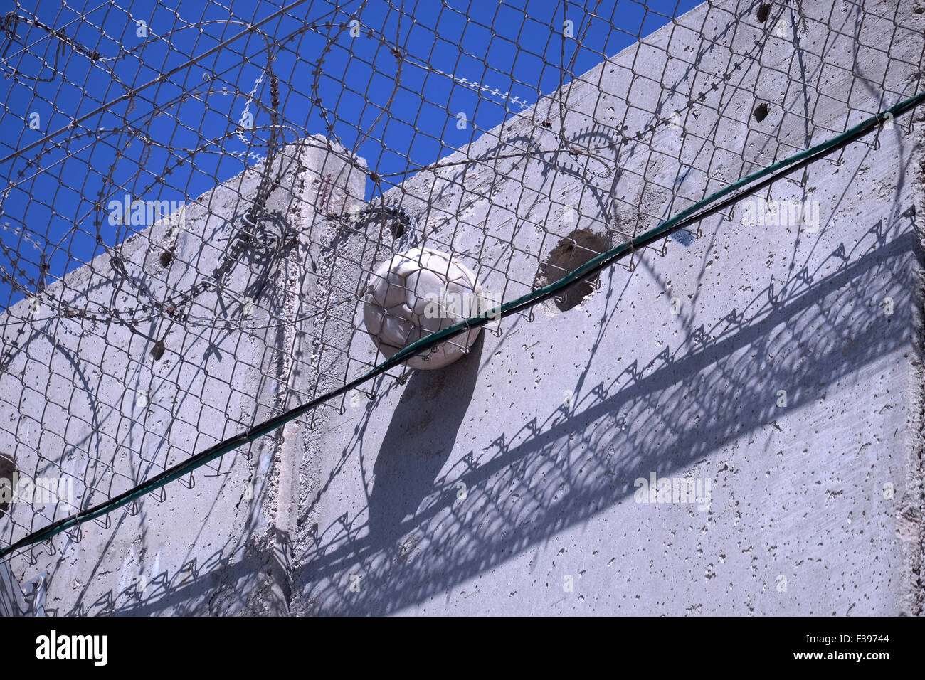 Un football coincé dans des fils barbelés au niveau de l'énorme barrière de séparation de Cisjordanie construite par Israël à Abu dis ou Abu Deis, une communauté palestinienne appartenant au gouvernorat palestinien de Jérusalem au sud-est de Jérusalem en Israël Banque D'Images