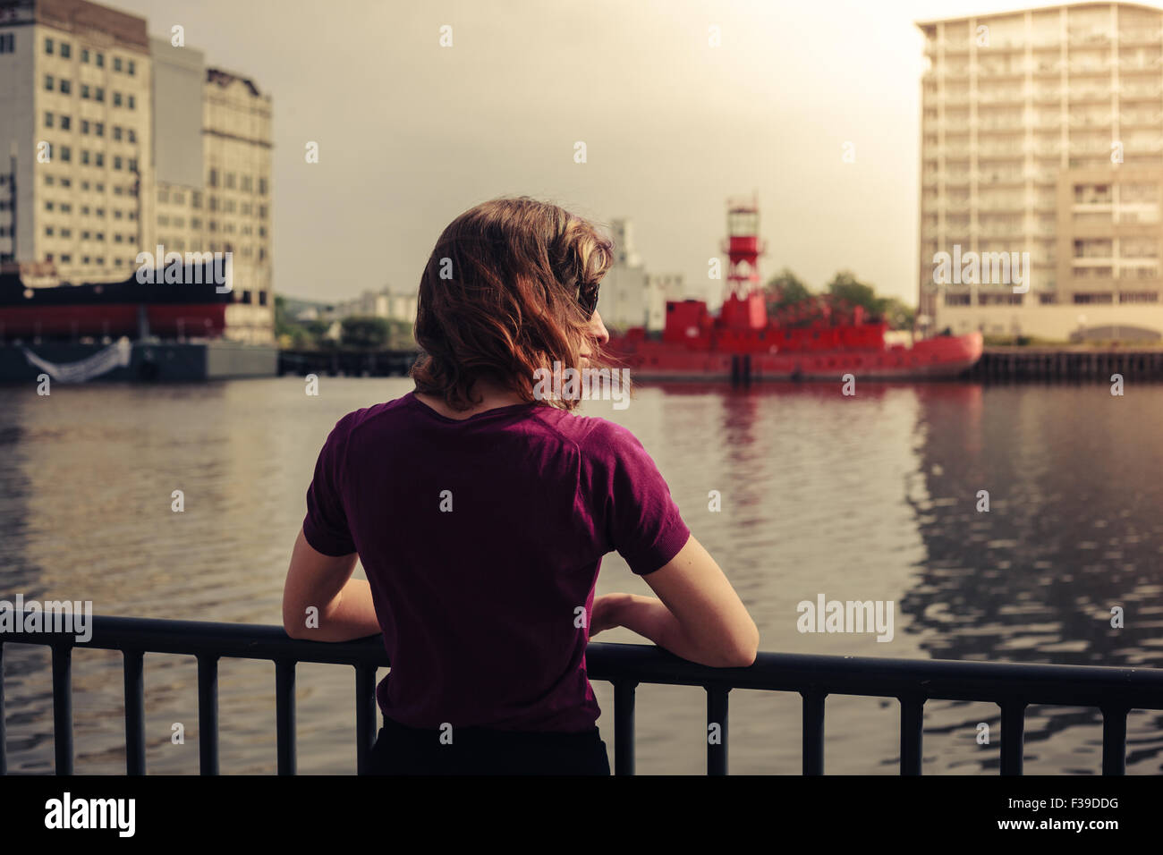 Une jeune femme est relaxant par une rivière et à la recherche à un bâtiment abandonné sur elle Banque D'Images