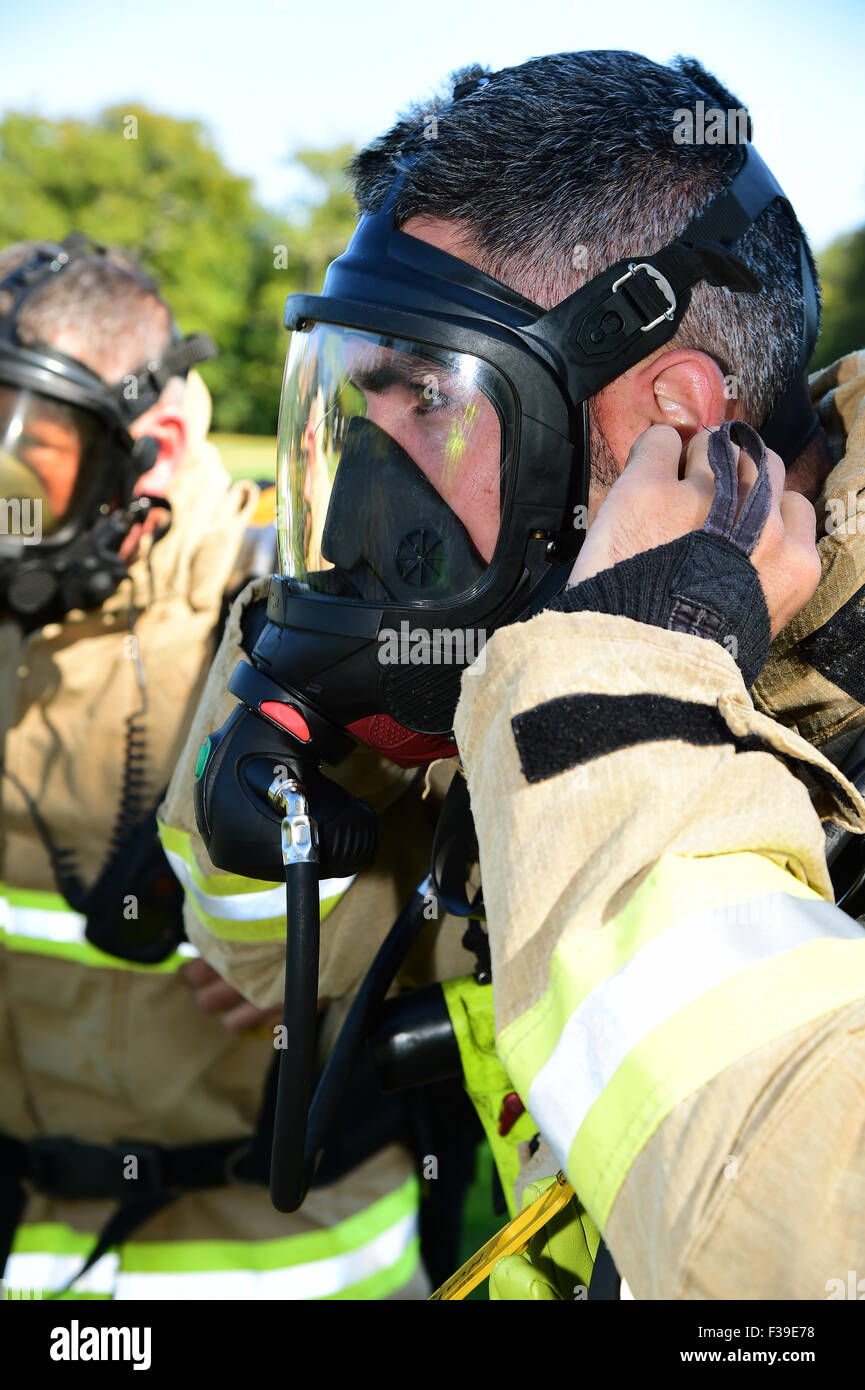 Pompier prépare son appareil respiratoire, contrôler son joint à face, sur les lieux d'un incendie. Banque D'Images