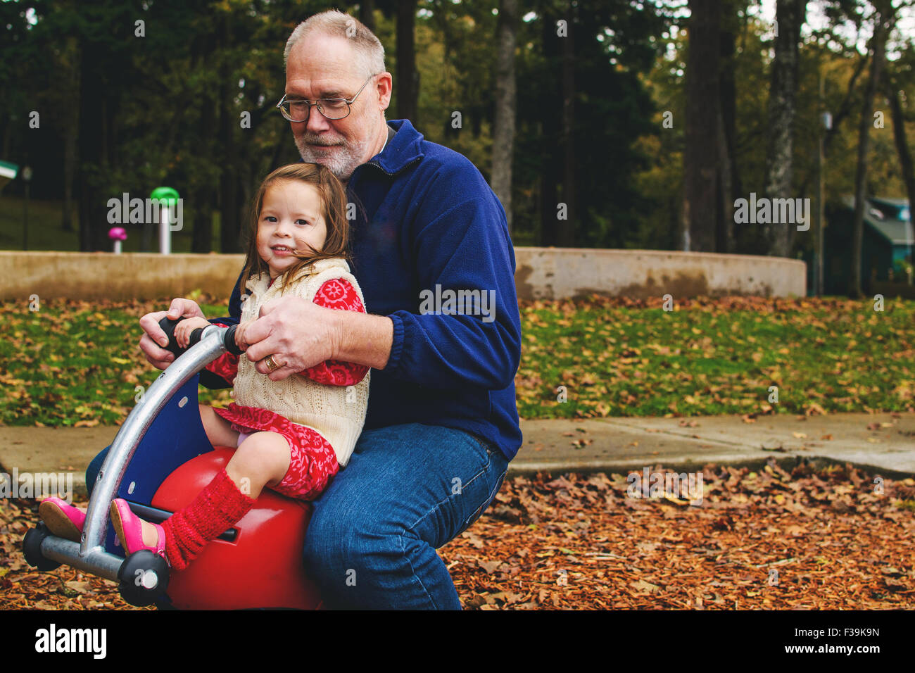 Fille jouant avec son grand-père à l'aire de jeux Banque D'Images