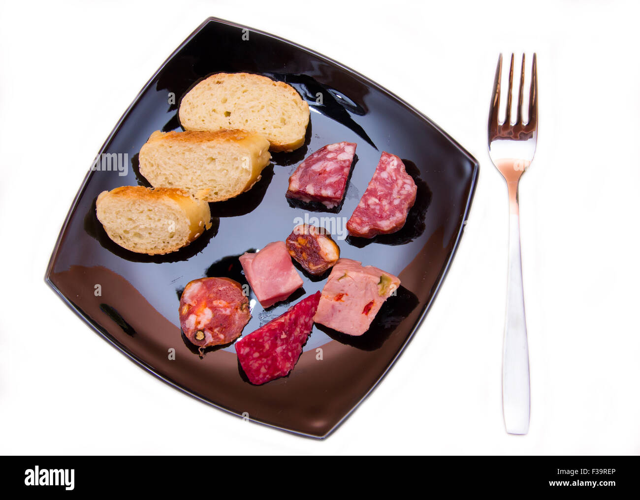 Morceaux de salami et de tranches de pain sur la plaque sur fond blanc vu de dessus Banque D'Images