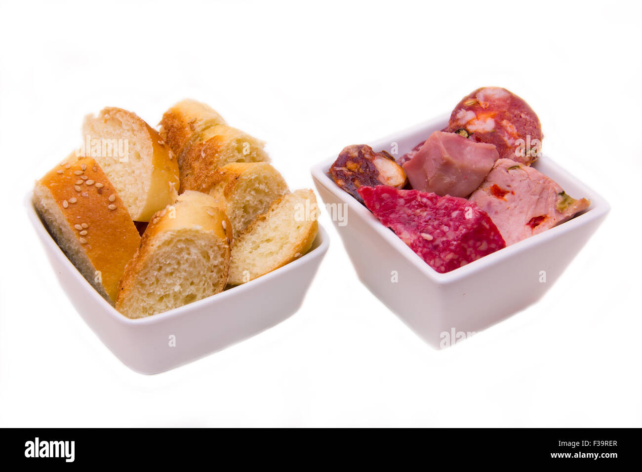 Morceaux de salami et les tranches de pain sur le bols sur fond blanc Banque D'Images