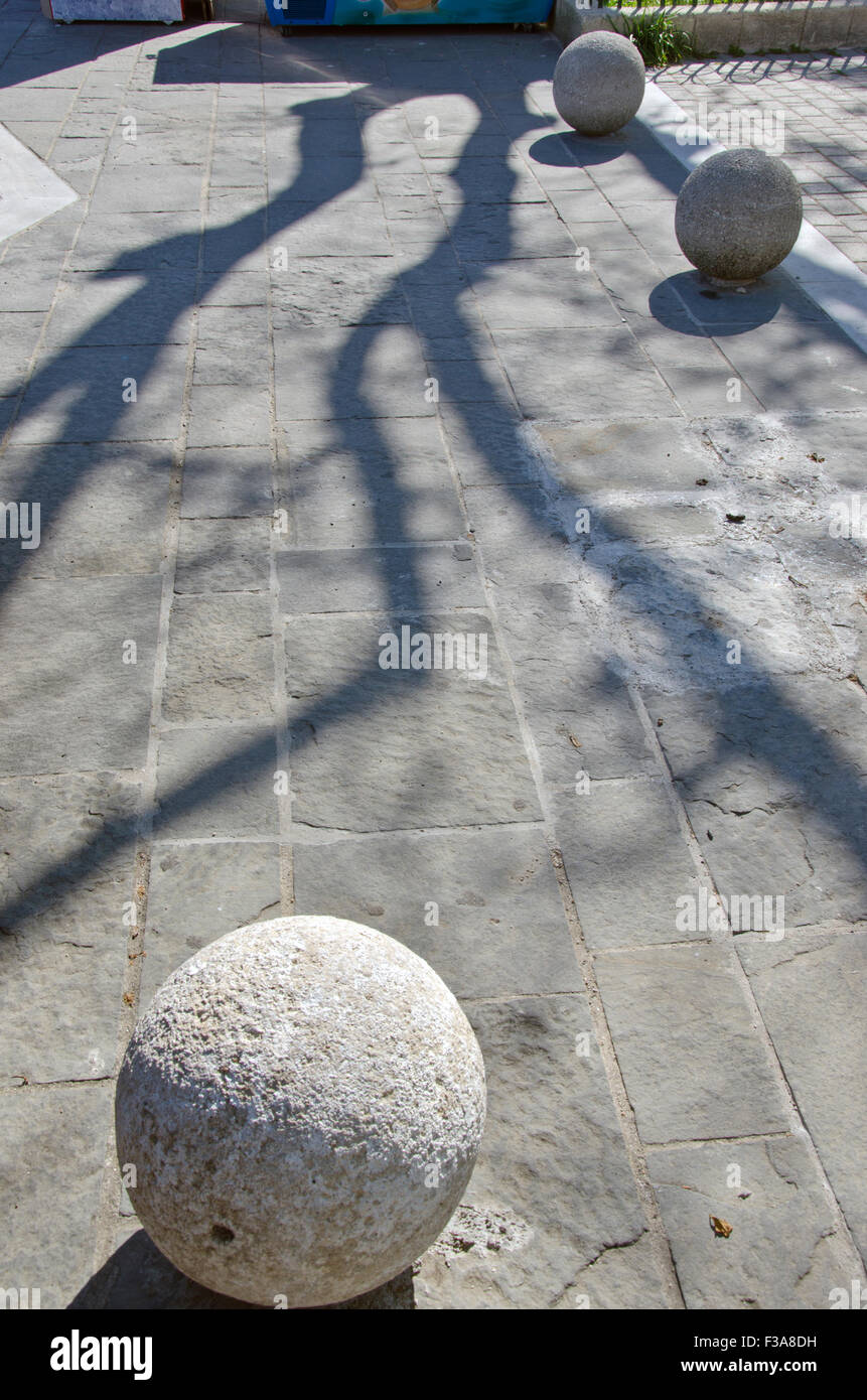 L'ombre des arbres sur la chaussée de la rue avec des boules en pierre décorative ronde Banque D'Images