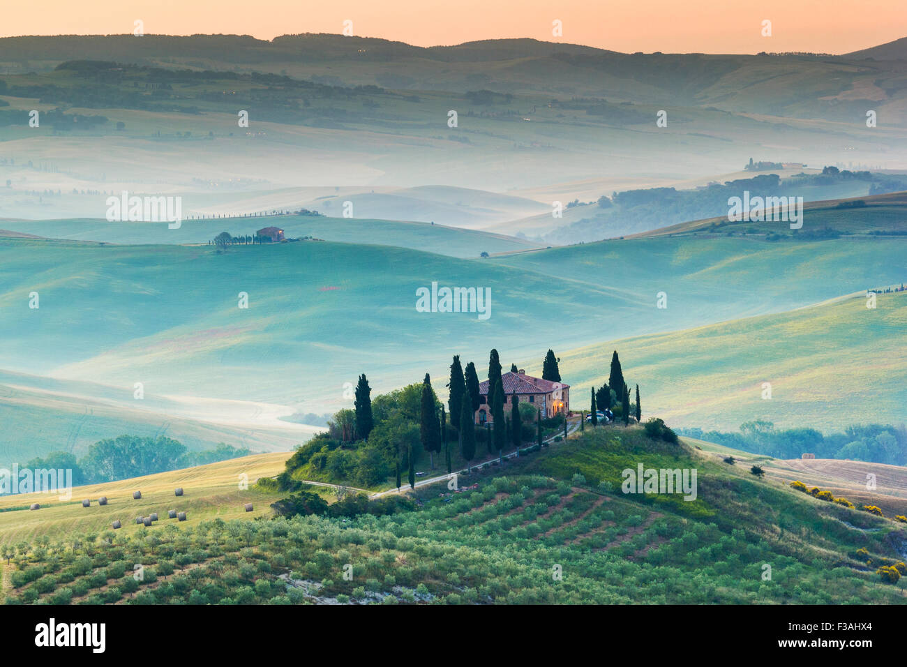 La toscane, ferme isolée dans le pays d'or et verts collines du Val d'Orcia, tôt le matin. Paysage italien. Banque D'Images