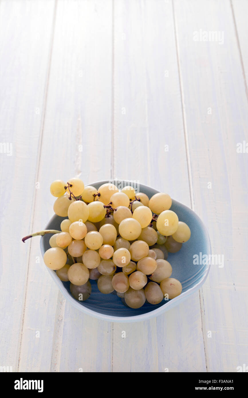 Raisins blancs dans un bol sur un tableau blanc Banque D'Images