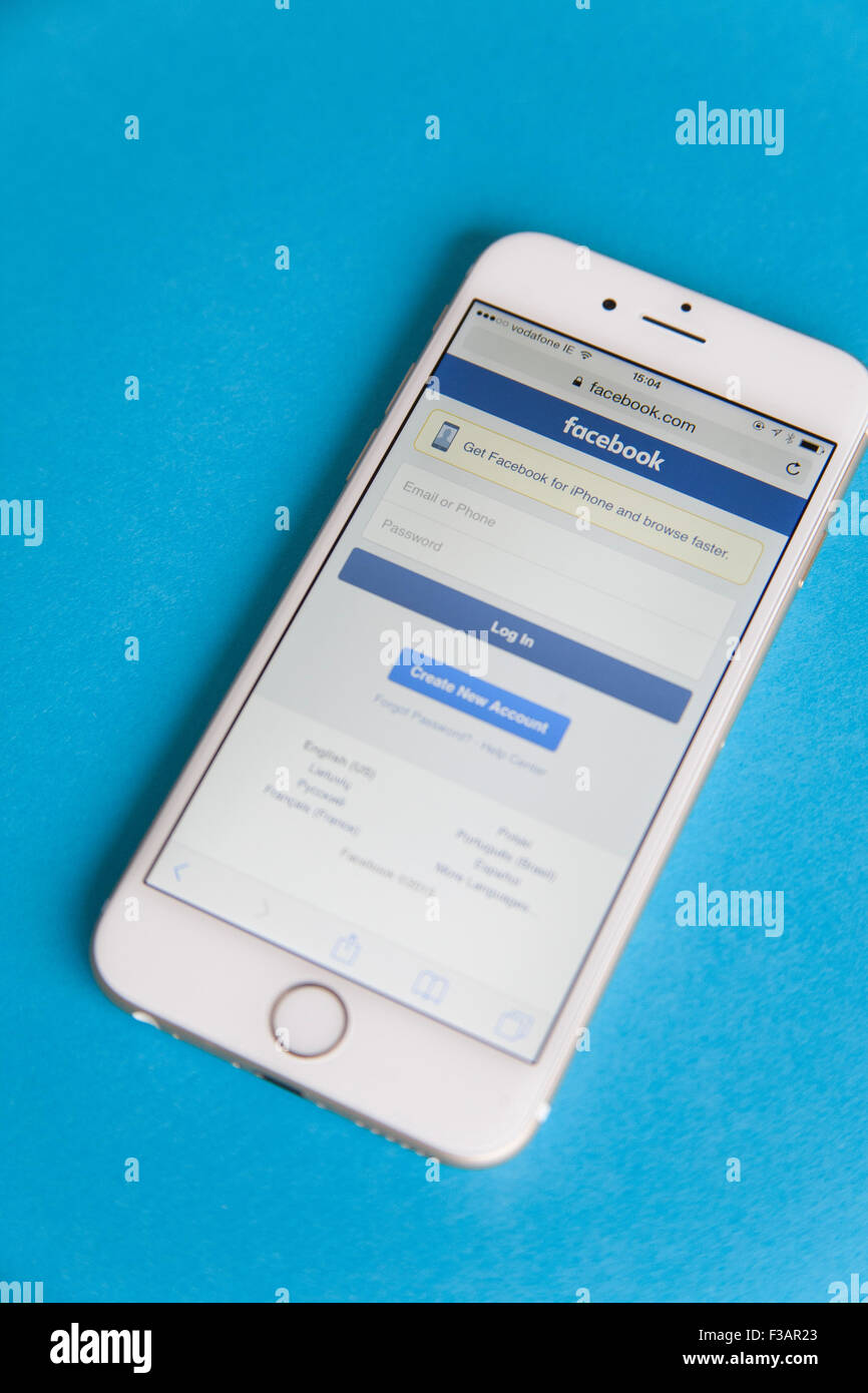 Or et blanc Apple iPhone 6 avec un écran Connexion à Facebook sur un fond bleu Banque D'Images