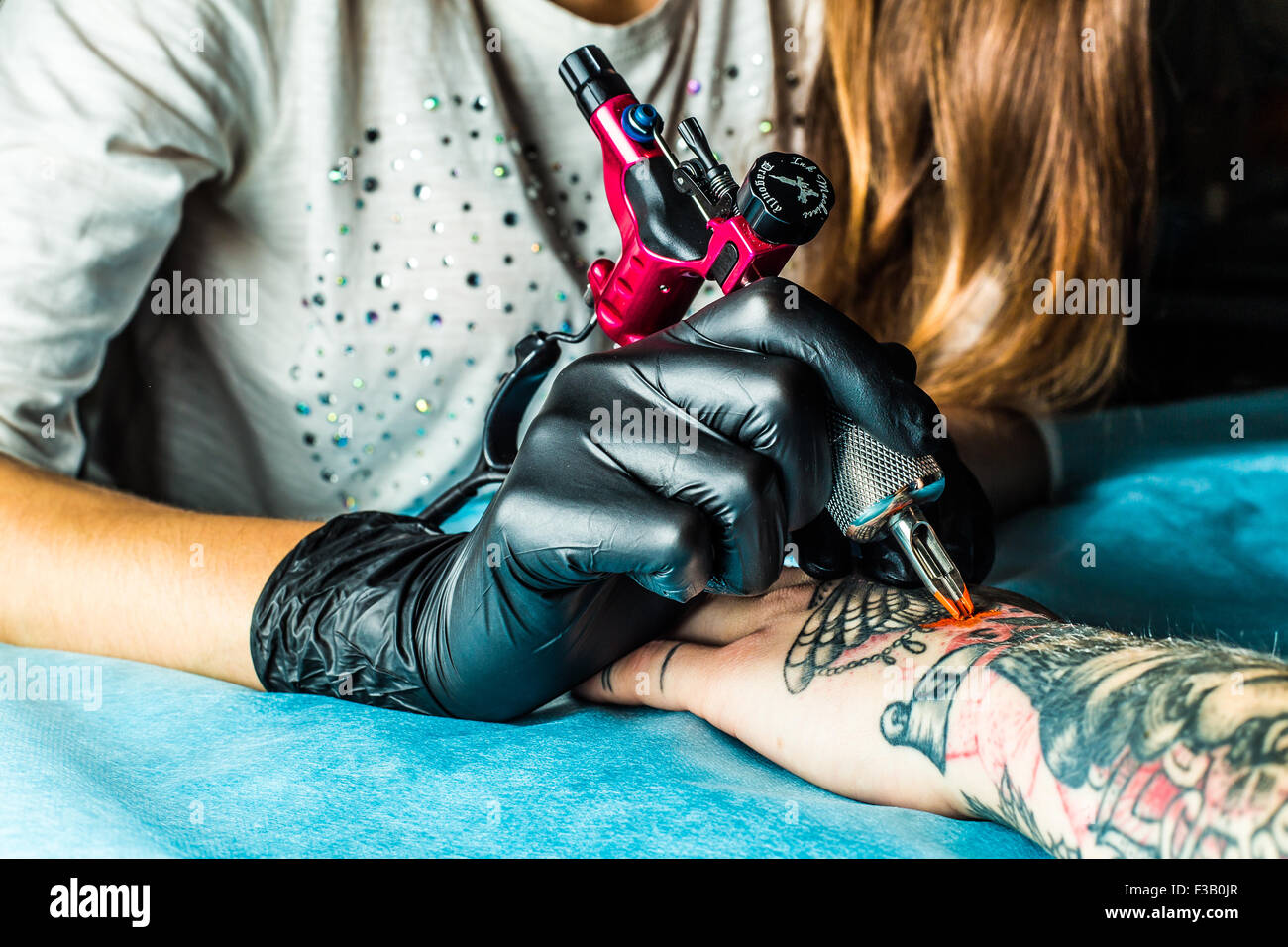 Tatouage maître attire les clients orange peinture sur main Banque D'Images