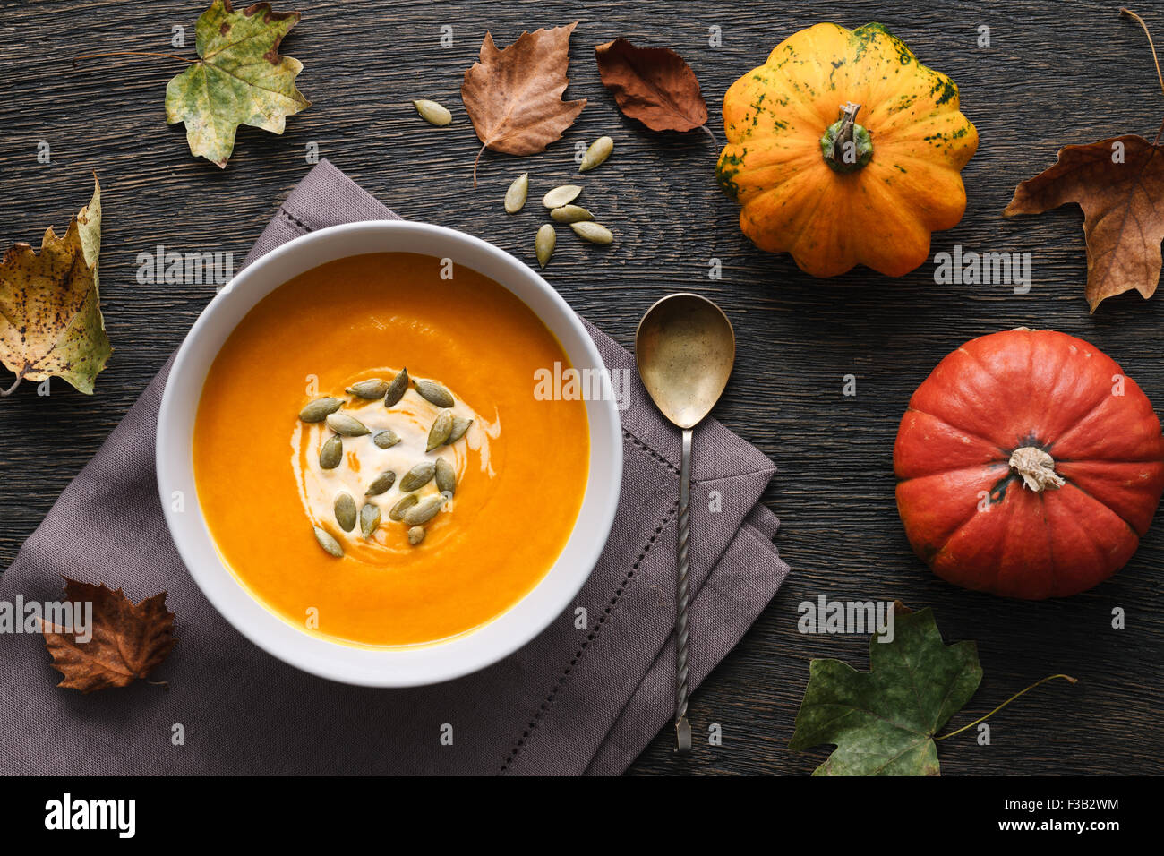 Soupe de potiron traditionnelle sur un fond de bois foncé avec les feuilles d'automne et de décoration de citrouilles. Banque D'Images