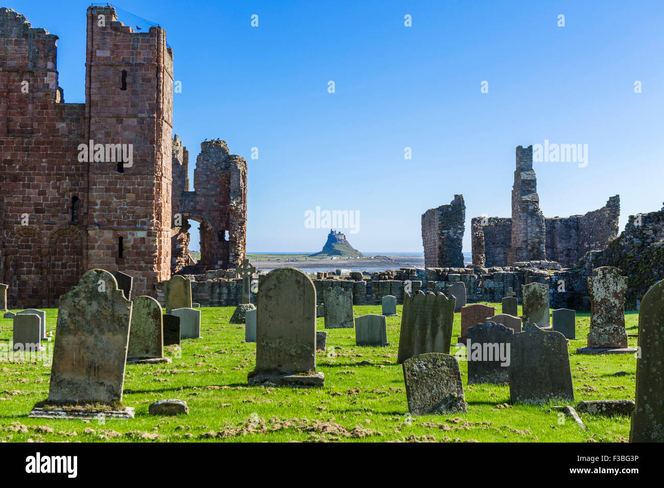 Les ruines de prieuré de Lindisfarne avec Château de Lindisfarne dans la distance, l'Île Sainte, Northumberland, England, UK Banque D'Images