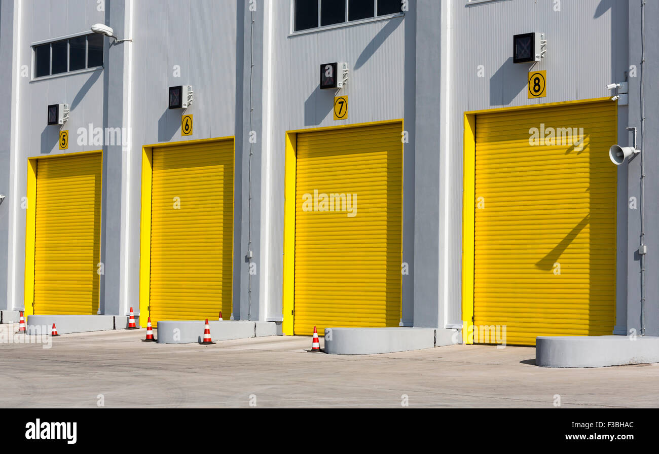 Quatre portes de garage jaune pour des camions de fret industriel. Banque D'Images