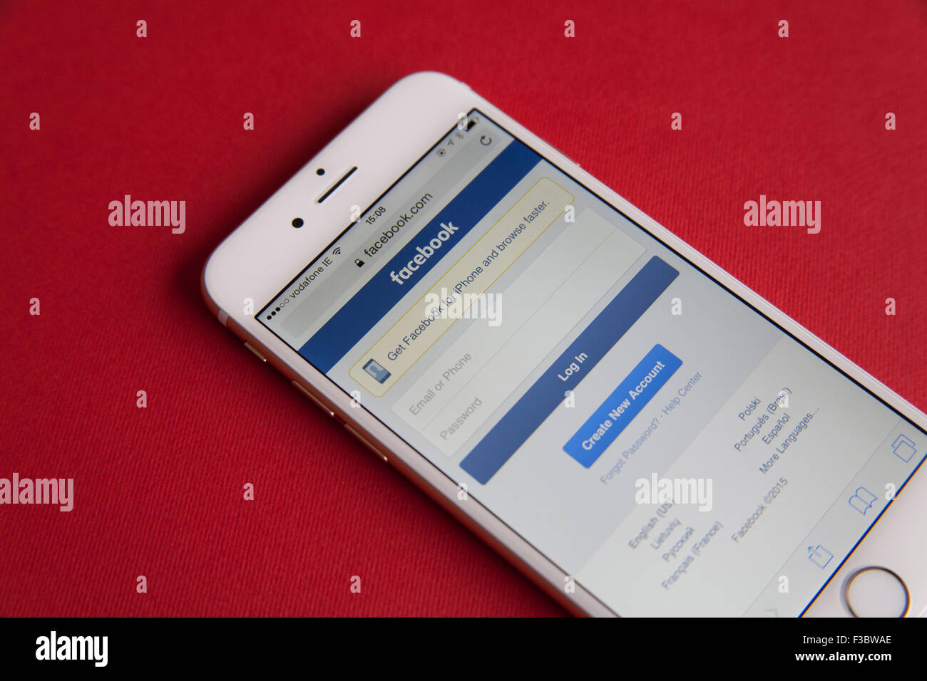 Or et blanc Apple iPhone 6 avec Facebook Connectez-vous sur l'écran sur un fond rouge Banque D'Images
