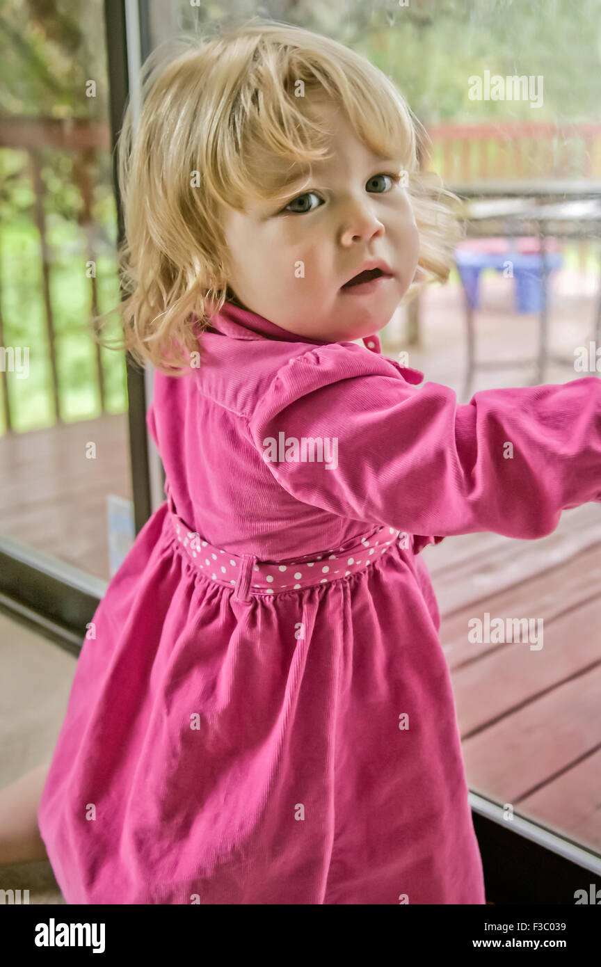 21 mois bébé fille debout à une porte coulissante en verre qui veulent  aller à l'extérieur après avoir fait quelque chose qu'elle n'était pas  supposé Photo Stock - Alamy
