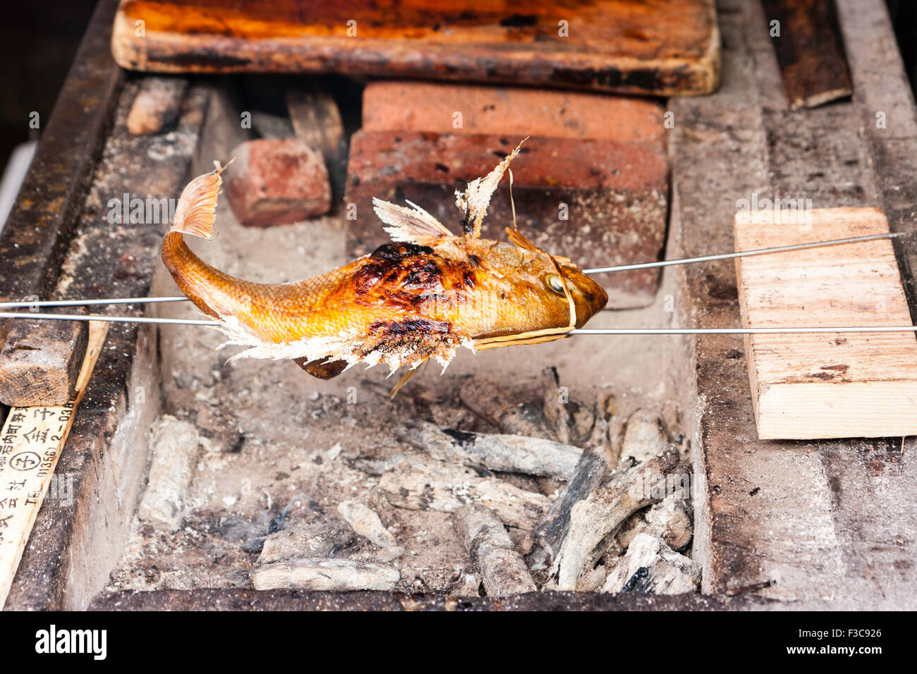 La mer poisson prisé faisceau asymétrique sur les cendres chaudes de style barbecue cuisinière à ouvrir le marché de Kuromon Ichiba à Osaka. De la mer est très populaire et apprécié. Banque D'Images