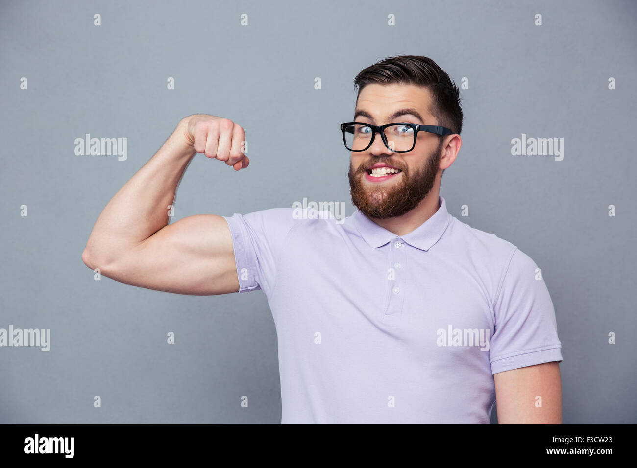 Portrait d'un homme drôle, dans les verres montrant ses muscles sur fond gris Banque D'Images