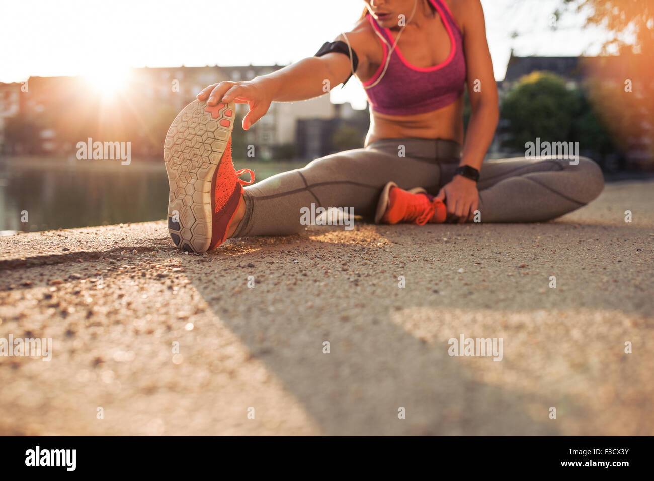 Cropped shot of female runner stretching jambes avant de faire son entraînement d'été. Femme de préchauffage avant d'entraînement en plein air avec chaises Banque D'Images