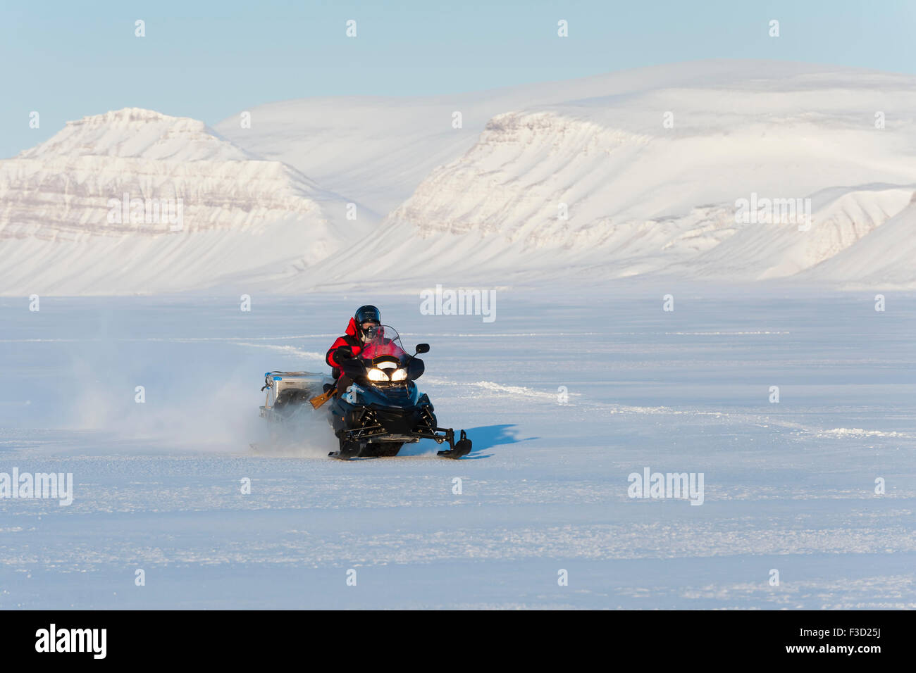 La motoneige en Tempelfjorden sur la glace de mer avec ses montagnes couvertes de neige, Spitsbergen, Svalbard, Norvège. Banque D'Images