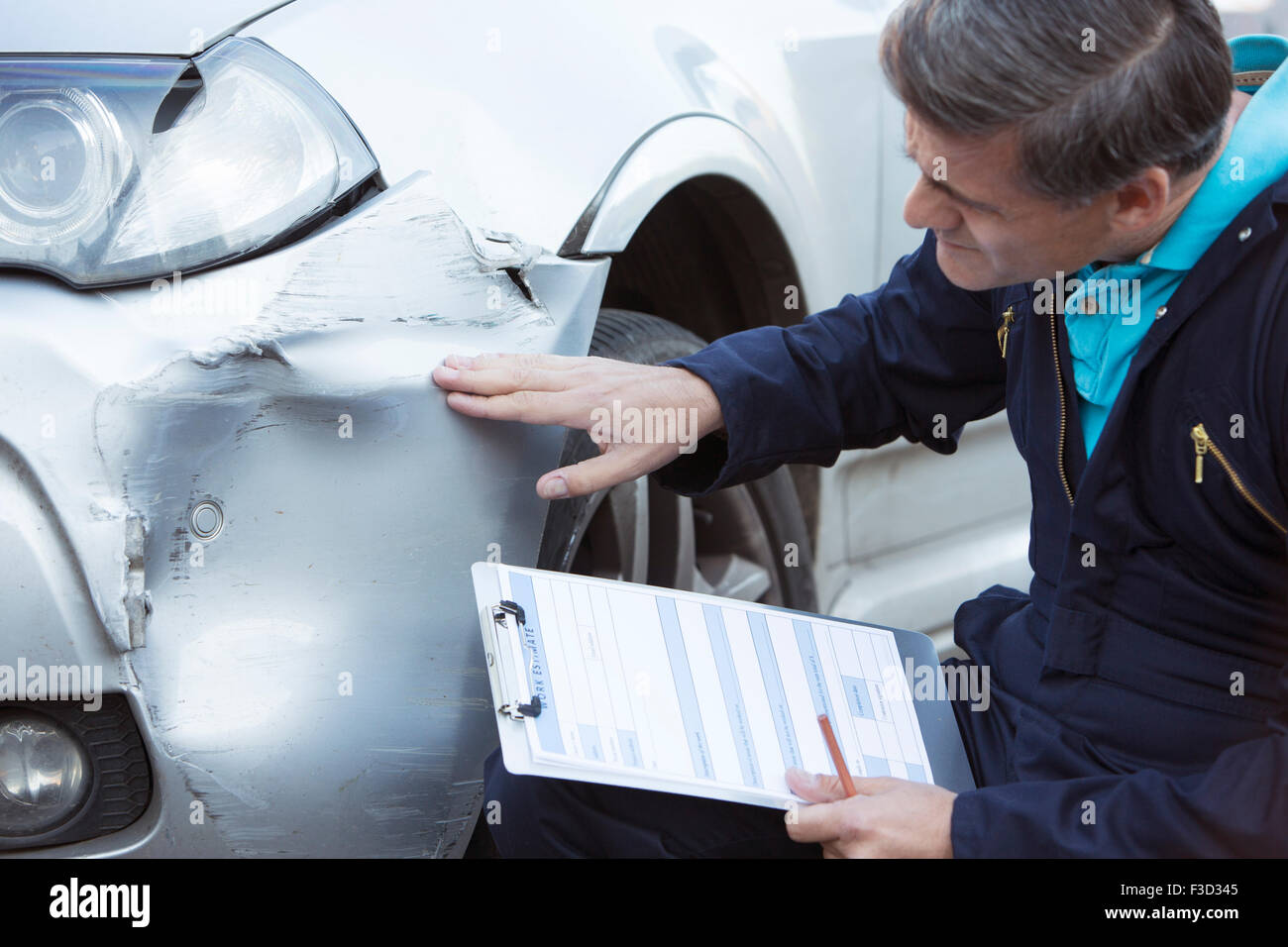 L'Inspection Mécanique Atelier auto voiture endommagé et de remplissage dans l'estimation des réparations Banque D'Images