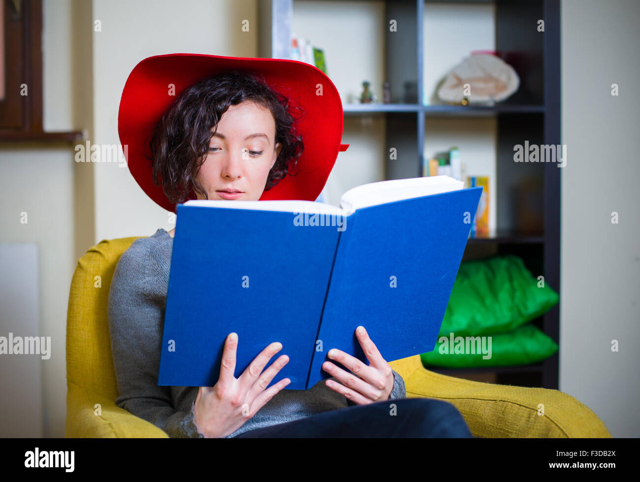 Jeune femme avec red hat de lire un livre avec couvercle bleu Banque D'Images