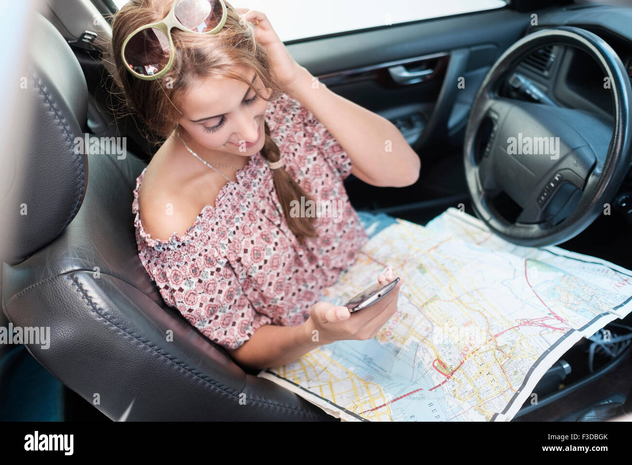 Woman téléphone en voiture avec la carte au tour Banque D'Images