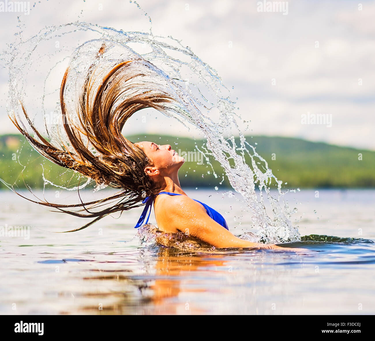 Jeune femme jetant cheveux en arrière dans le lac Banque D'Images