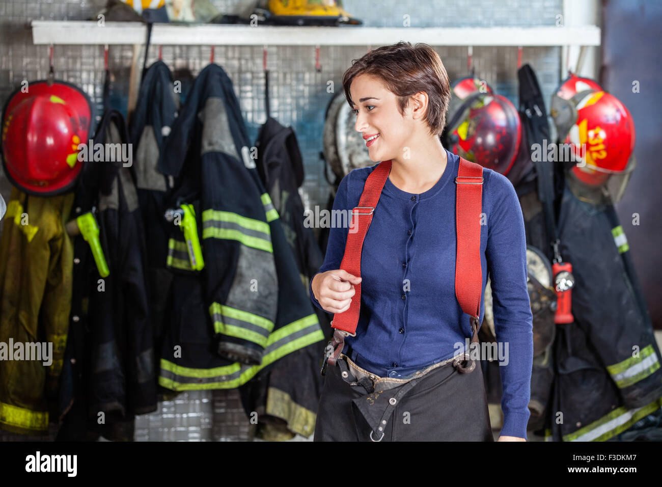 Debout contre des uniformes à pompier fire station Banque D'Images