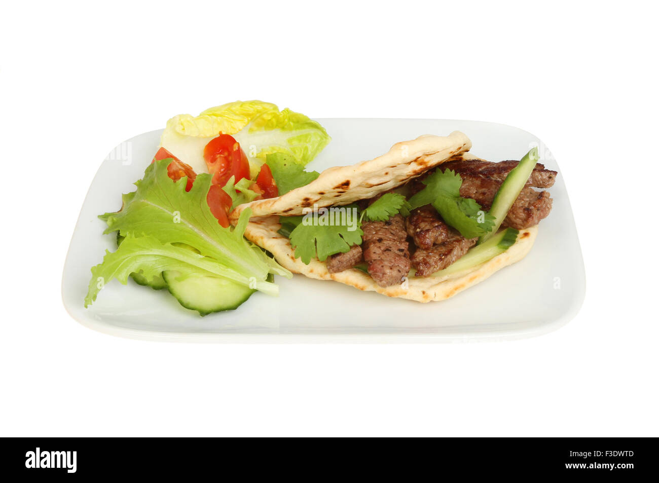 Fried steak minute dans un pain plat style kebab avec de la salade sur une assiette blanche contre isolés Banque D'Images