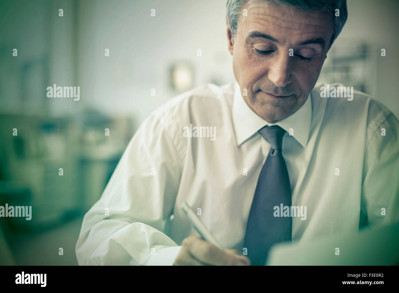 Mature businessman writing in office Banque D'Images
