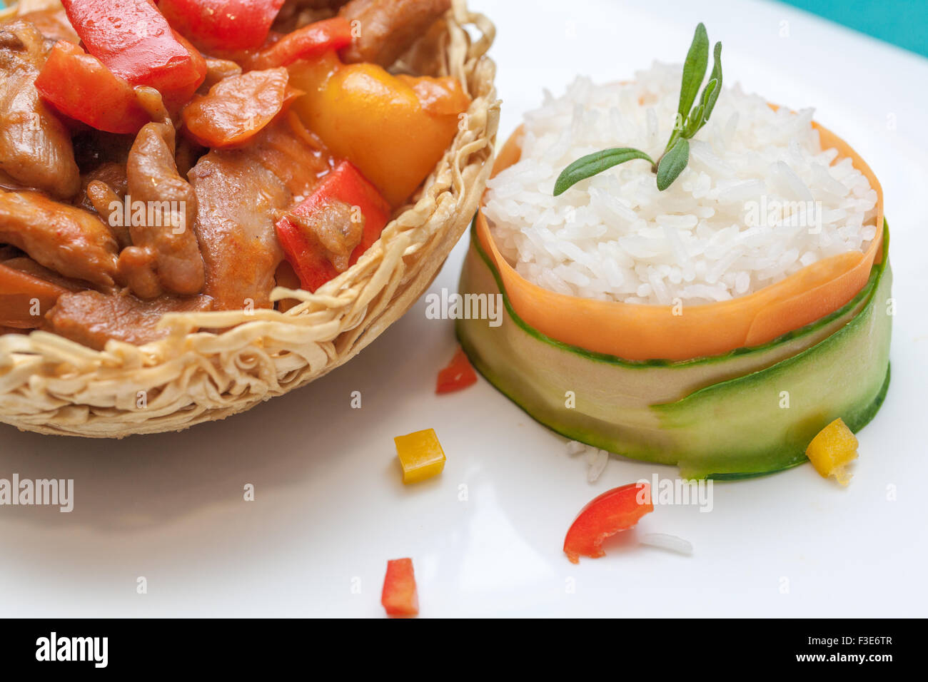 Mets chinois, poulet avec des poivrons verts doux dans un nid de nouilles frites et étuvé lieu décoré avec le concombre et la carotte de côté Banque D'Images