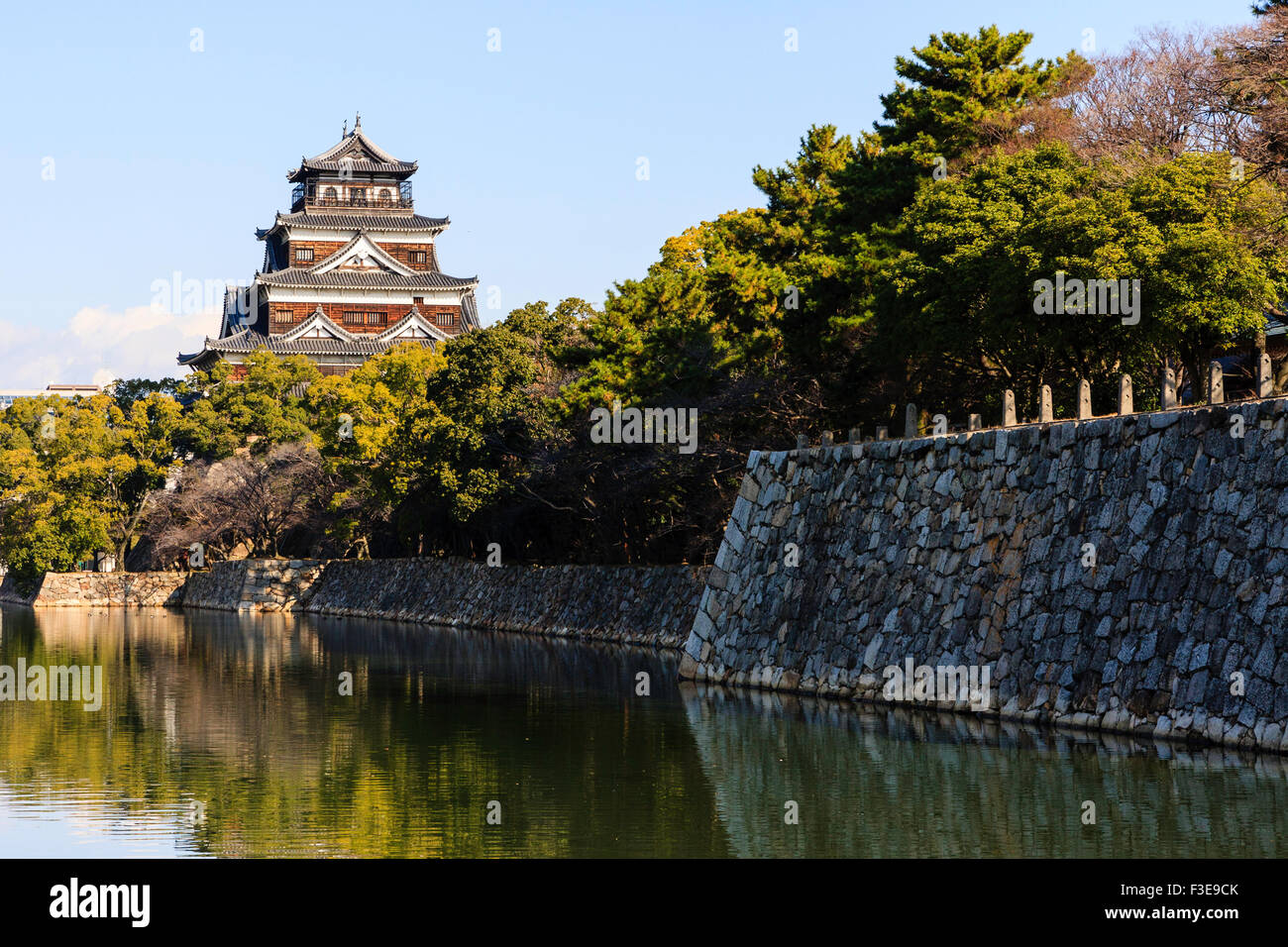 Château d'Hiroshima. Borogata reconstruit avec des arbres autour de type garder. Premier plan le fossé et Honmaru Ishigaki mur de pierre Banque D'Images