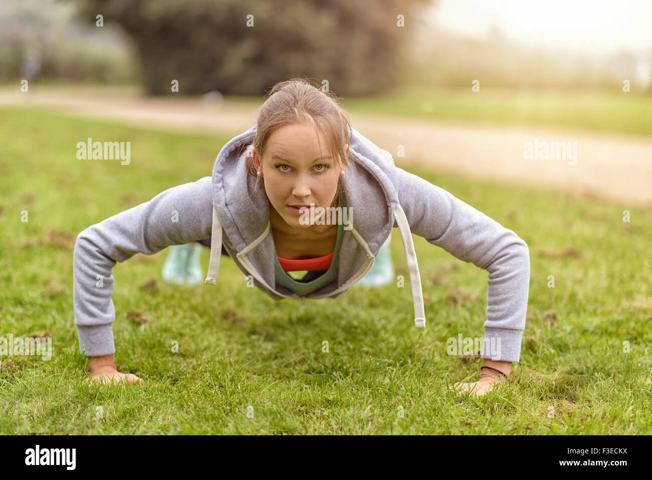 Athletic Young Woman Smiling at the camera tout en faisant pousser l'exercice jusqu'au parc. Banque D'Images