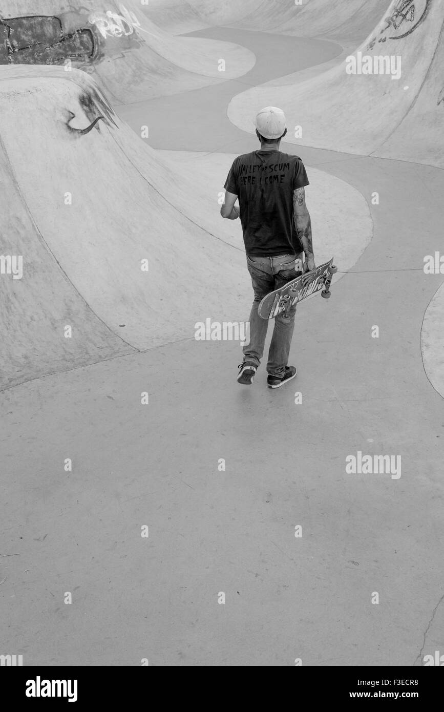 Vue arrière de l'adulte à marcher avec l'intérieur de skateboard skate park Banque D'Images