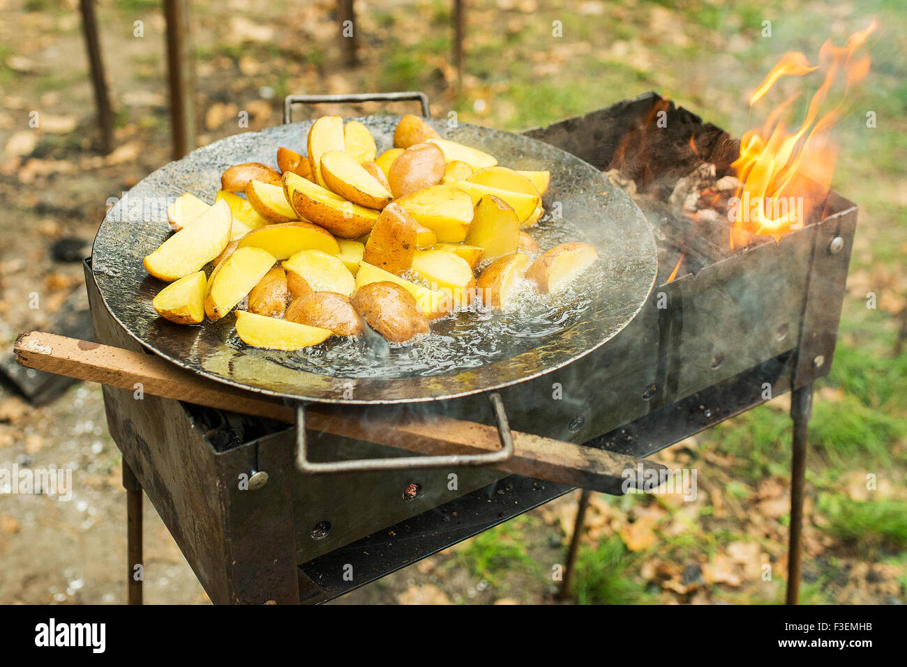 La pomme de terre frite dans big melal pot. Sur le gril et ouvrir le feu, fumée. Banque D'Images