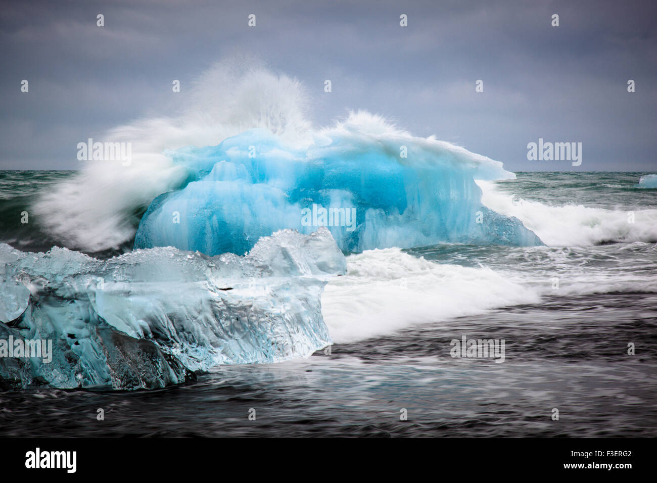 De grosses vagues fracassant contre un gros iceberg dans la mer ouverte, Jökulsarlon, Islande Banque D'Images