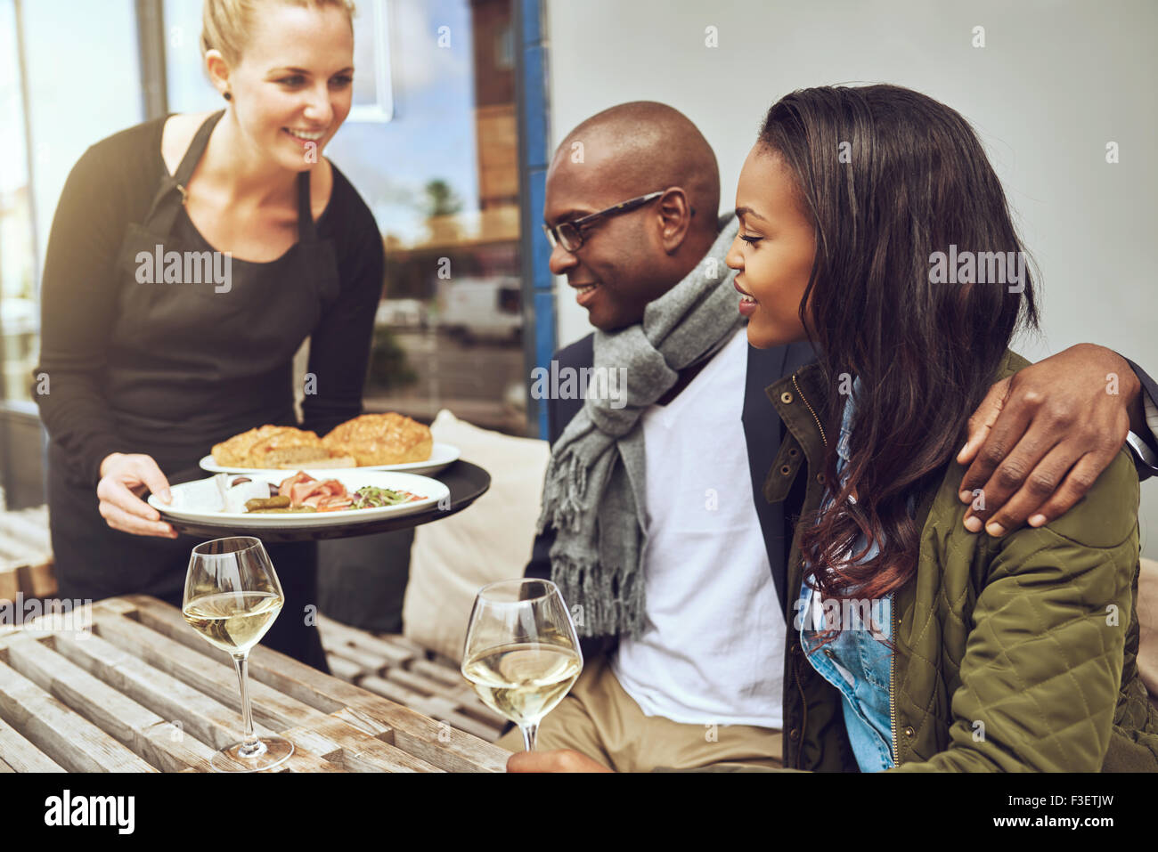 Waitress une affectueuse African American couple assis dans les bras à une table de restaurant Banque D'Images